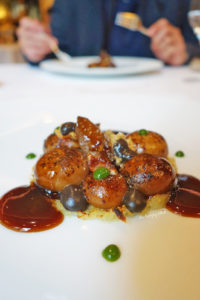 Gratinated onions, contemporary Parisian style. Spherified onion soup, black truffle emulsion, croutons, demi, on a bed of melted cheese